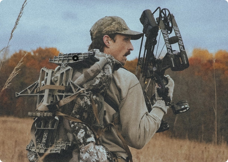 Man in camouflage gear with a bow and quiver in an outdoor setting